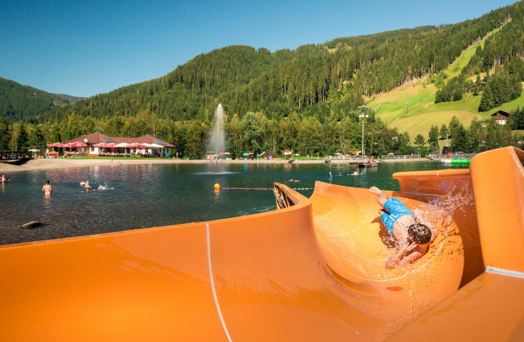 Kind rutscht auf der Rutsche am Badesee in Eben im Pongau